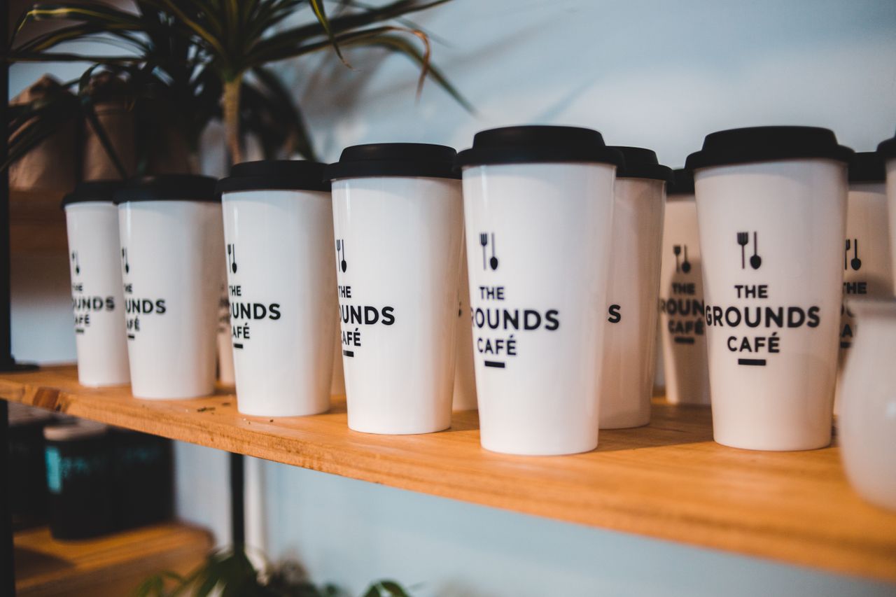 Designed white for coffee with black silicone lids and cutlery symbols on shelf for sale in coffee shop