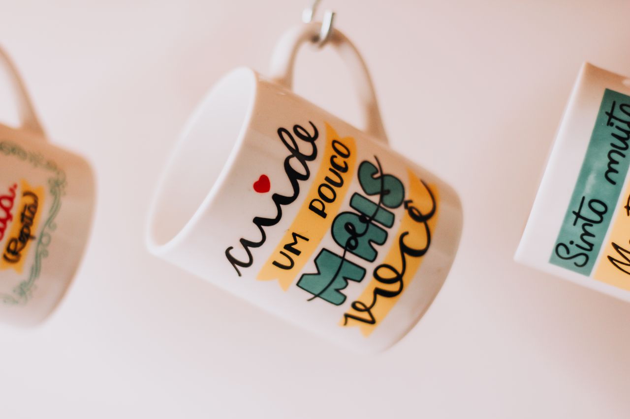 Close-up of hanging mugs with motivational text in São Paulo, Brazil.